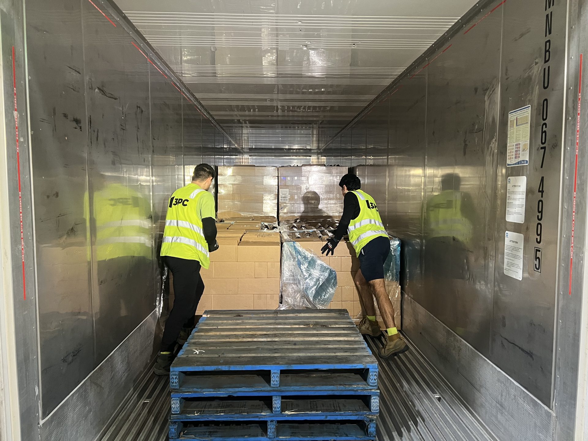Crew hand-unloading a shipping container